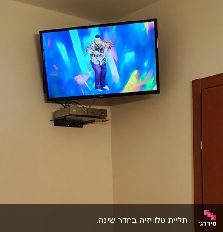 טלוויזיה מותקנת על הקיר עם ממיר מתחתיה